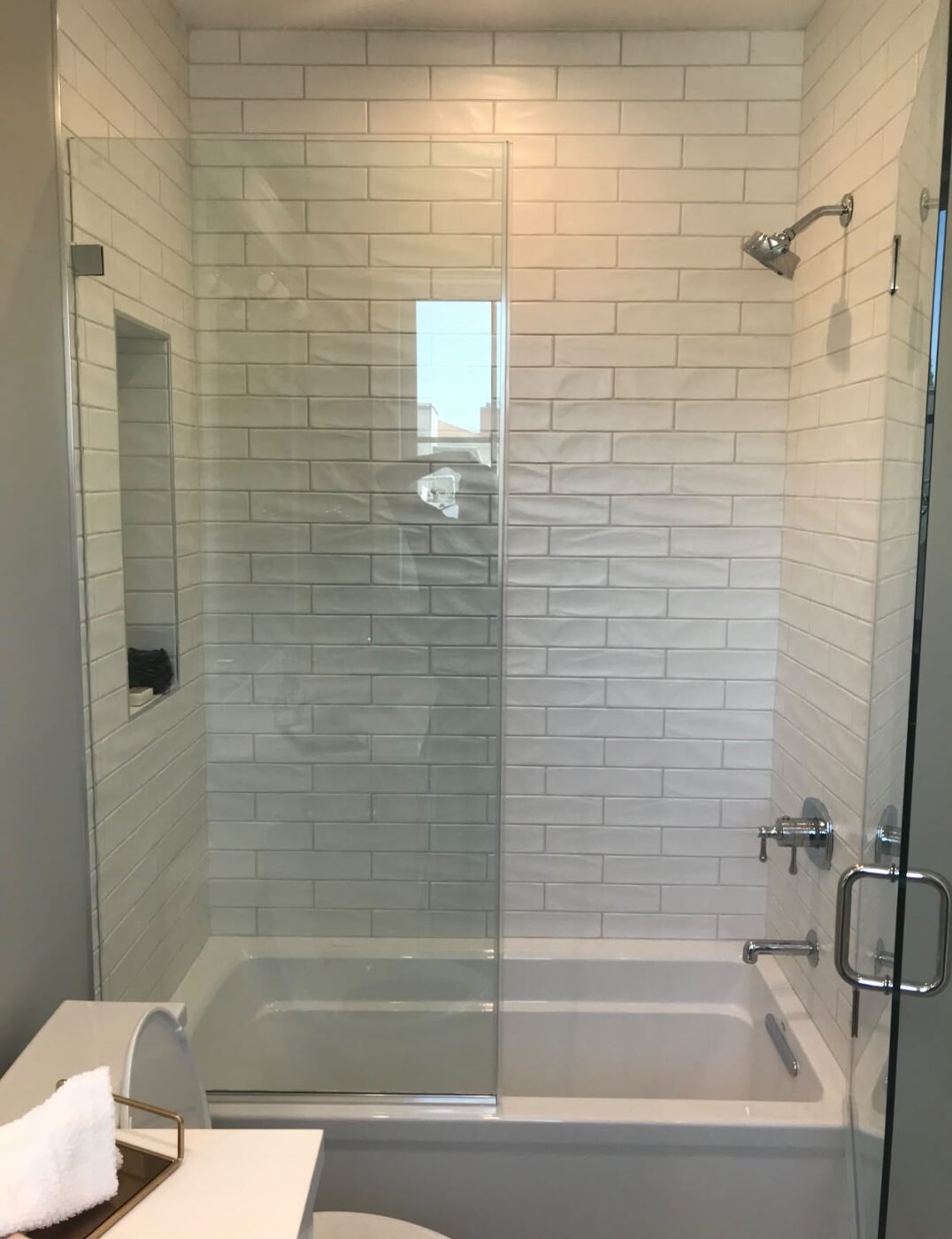 Frameless shower glass over tub with subway tile by NG Windows and Doors